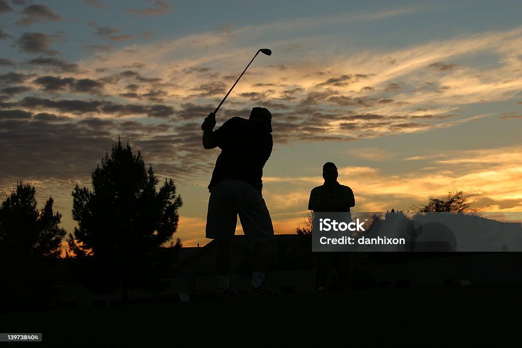 Swing at Sunset Men playing golf at sunset. Aiming Stock Photo