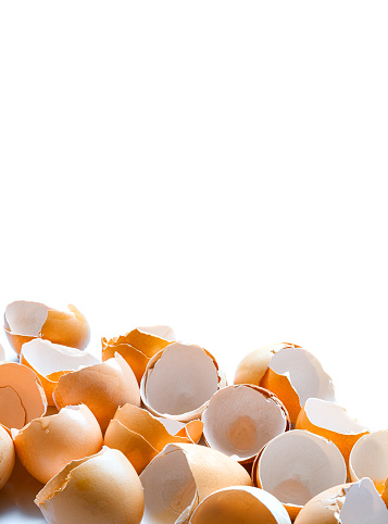 a pile of broken brown egg shells empty without protein content garbage after cooking, vertical banner on white background with copy space.