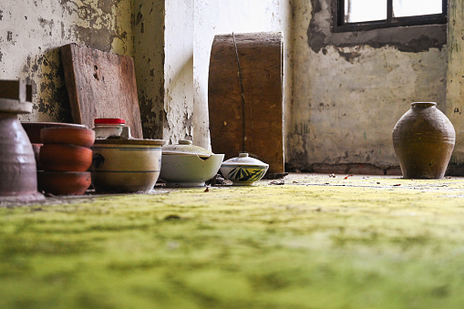 Dilapidated house and ceramic utensils on the ground