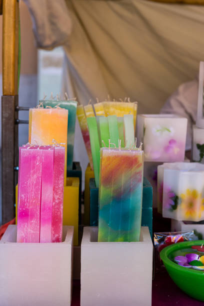 A stall during a handicraft fair, beautiful wax candles in different colors on white pots