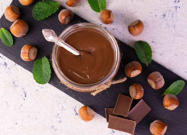 istock Chocolate spread with hazelnuts in a jar on a black slate board. Flat lay. 1397389161