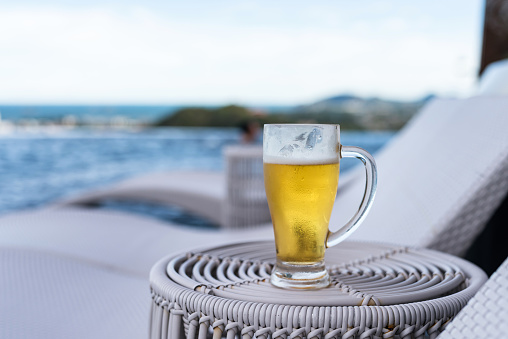Fresh cold beer at rooftop swimming pool with blur sea view in Hua Hin
