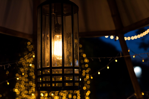 Hanging lantern lamp with bokeh light background at night.Outdoor light up decoration in wedding reception party.