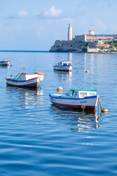 Fishing Boats In Bay of Water Havana, Cuba - May 12, 2022:  Small fishing boats are moored in the bay by the Malecon seawall. There are no people in the scene. El Morro castle is in the background. This area is a tourist attraction. morro castle havana stock pictures, royalty-free photos & images