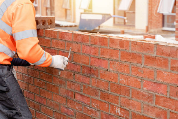 bricklayer laying bricks on mortar on new residential house construction - brick cement bricklayer construction imagens e fotografias de stock