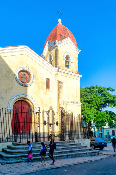 Havana, Cuba - May 24, 2022: A family walks in front of the Parroquia de Jesus, Maria y Jose. The children are wearing school uniform. The religious building is located in Vives # 103 e/ Águila y Revillagigedo in Old Havana.