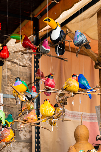 At a craft fair, beautiful wooden birds in different bright colors hung on strings.