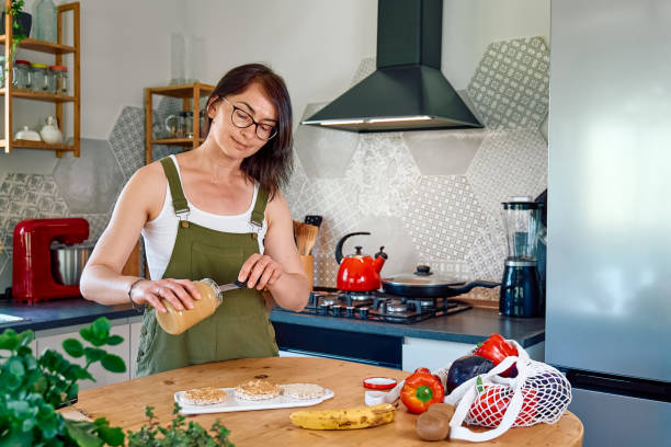 istock Woman making healthy breakfast or brunch, spreading peanut butter on a puffed corn cakes. Protein diet healthy eating concept. 1397392814