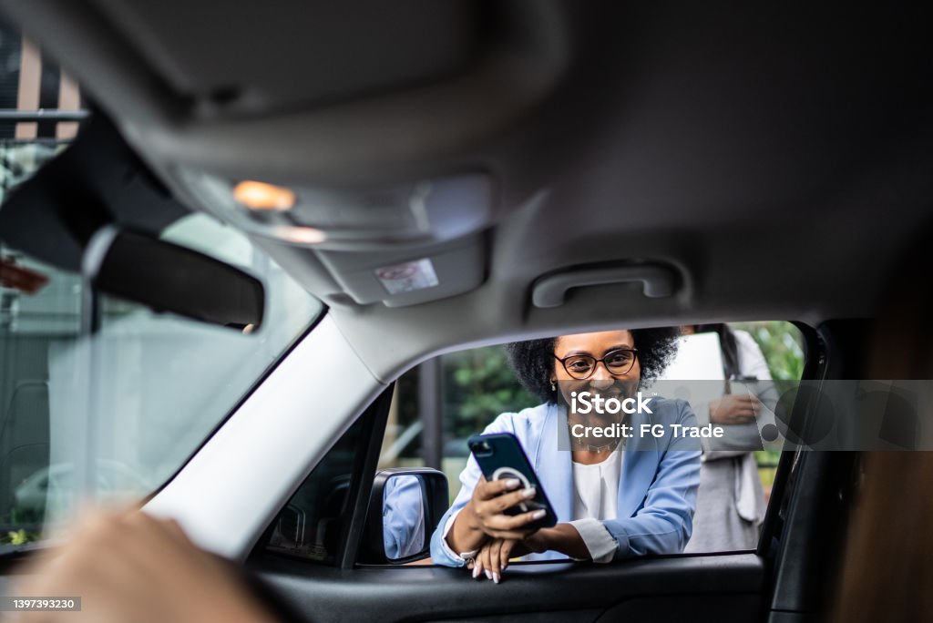 Businesswoman using smartphone talking to cab driver through the car window Taxi Driver Stock Photo