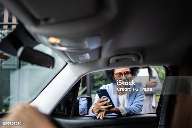 Businesswoman Using Smartphone Talking To Cab Driver Through The Car Window Stock Photo - Download Image Now