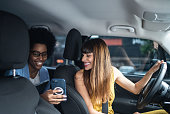 Passenger talking to cab driver and showing her the smartphone