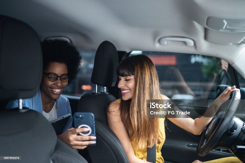 Passenger talking to cab driver and showing her the smartphone Crowdsourced Taxi Stock Photo