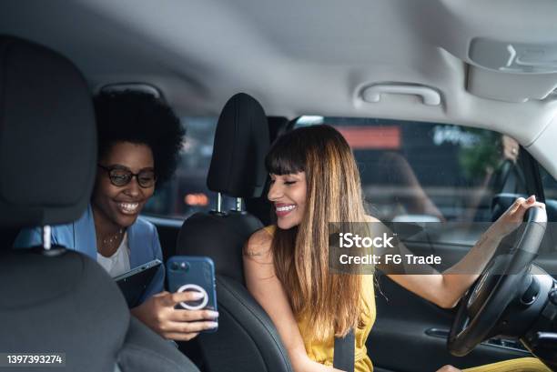 Passenger Talking To Cab Driver And Showing Her The Smartphone Stock Photo - Download Image Now