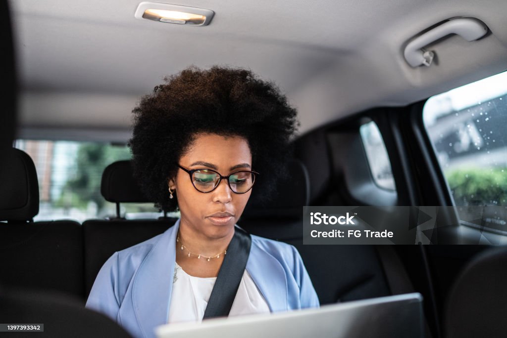Business woman using laptop in a cab Focused business woman using laptop in a cab Car Pooling Stock Photo