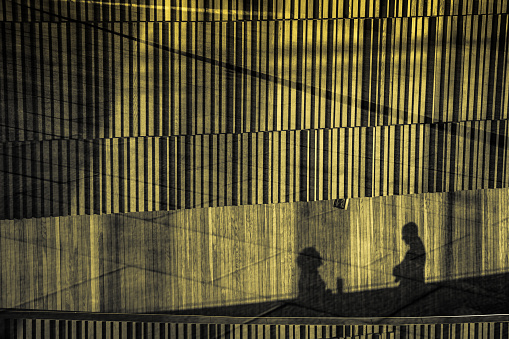 Silhouettes of a woman and man having a conversation on the walkway in front of the Oslo Opera House.