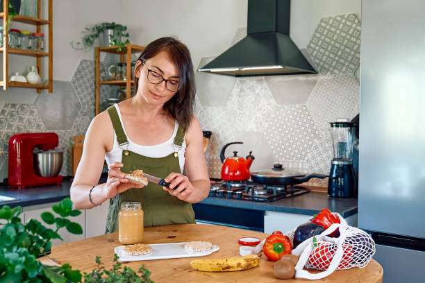 istock Woman making healthy breakfast or brunch, spreading peanut butter on a puffed corn cakes. Protein diet healthy eating concept. 1397394166