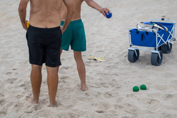 two men on the beach playing bocci ball with a blue beach cart