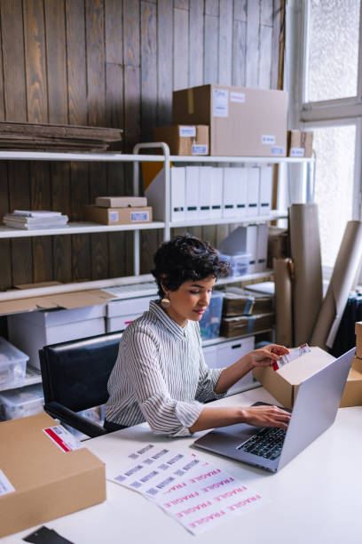 une femme d’affaires intelligente assise et travaillant sur son ordinateur portable au bureau - packaging tape photos et images de collection