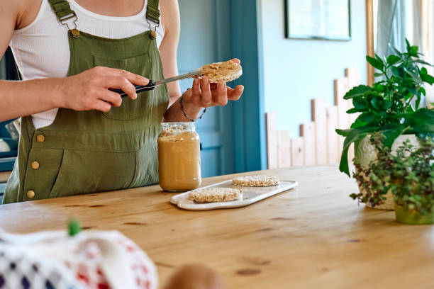istock Woman making healthy breakfast or brunch, spreading peanut butter on a puffed corn cakes. Protein diet healthy eating concept. 1397395431