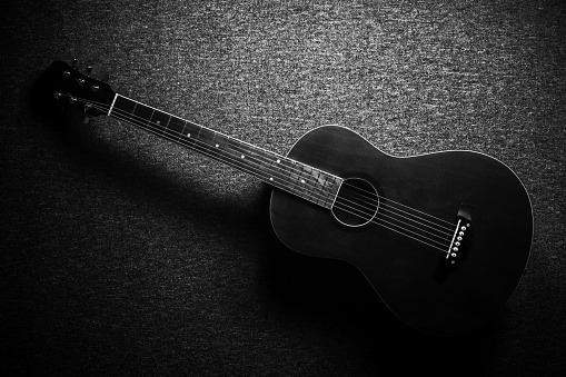 Black acoustic guitar studio shot on black background with copyspace, Guitar is favorite music instrument for hobby.