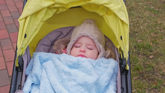 Cute CaucasianToddler Baby Girl Sleeping in Pram Stroller Perambulator under Warm Fluffy Blanket