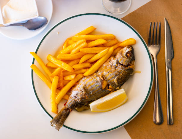 Fried Mediterranean fish Sarpa Fried Sarpa salpa fish with potatoes and lemon close-up on a plate salpa stock pictures, royalty-free photos & images