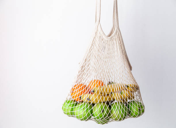 istock White string bag with green apples, oranges and bananas on a white background. 1397402149