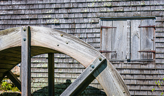 The wooden water wheel and shuttered window of the old Dexter  Grist Mill (1638) in Sandwich, Massachusetts