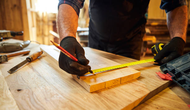 istock Carpenter working with a wood, marking plank with a pencil and taking measurements to cut a piece of wood to make a piece of furniture in a carpentry workshop, close-up view 1397404603