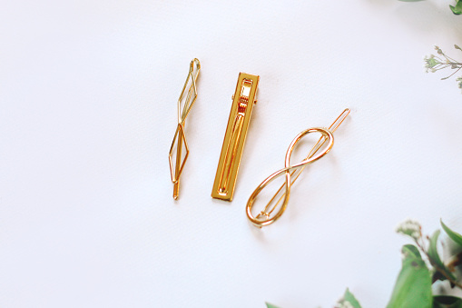 Fashionable hair clips with gold on a background with green plants.