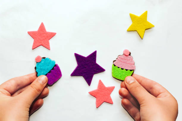 子供の手は星とカップケーキのフェルトステッカーのアップリケを作ります - appliqué ストックフォトと画像