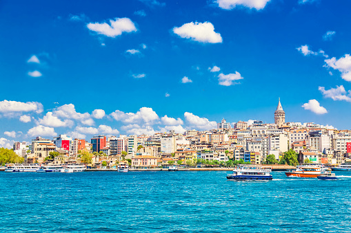 Beyoglu historic district and Galata tower medieval landmark with sightseeing ships. Istanbul, Turkey.