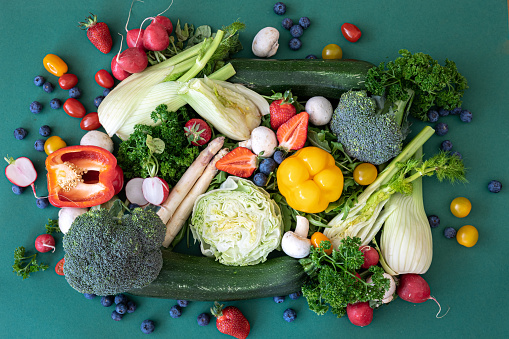Close-up, bright fresh vegetables, fruits and berries on a green background, flat lay.