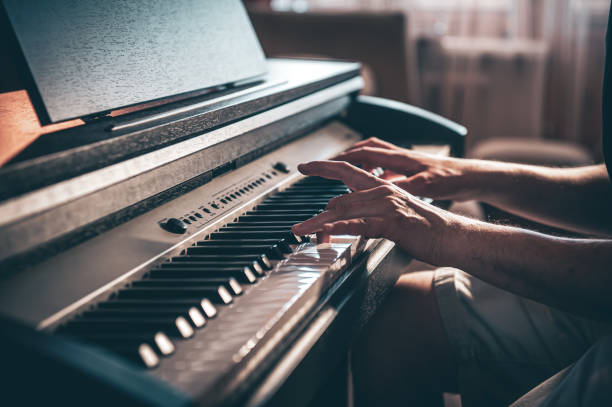 istock A man plays an electronic piano in a dark room. 1397405930