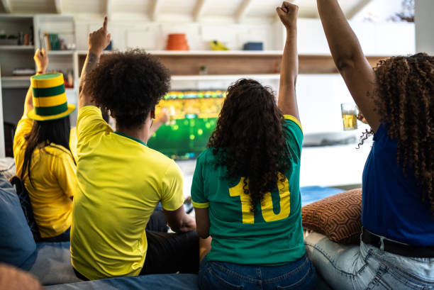 friends celebrating a goal while watching a soccer match at home - fan television football watching tv imagens e fotografias de stock