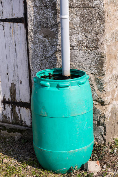 istock Green plastic barrel collects rainwater from a spout outside a stable. 1397409374