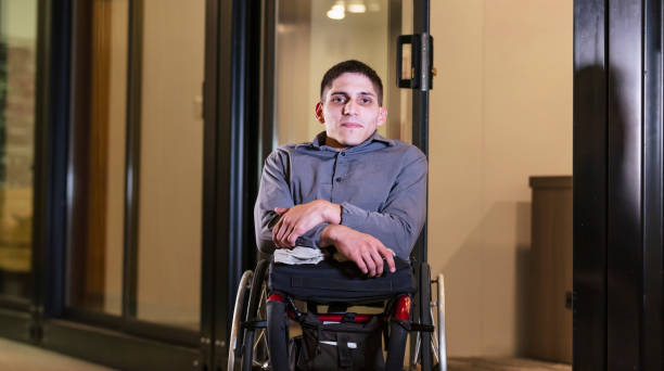 istock Young man in wheelchair, in office corridor 1397410273