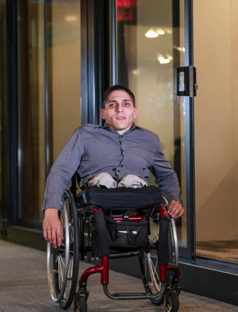 istock Young man in wheelchair, in office corridor 1397410297