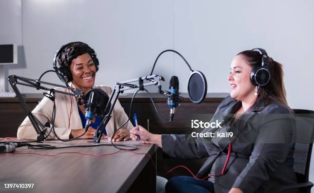 Two multiracial women recording a podcast