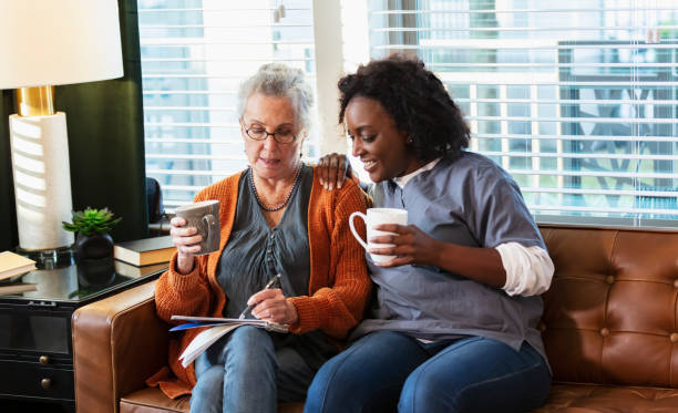 istock Senior woman, home caregiver on sofa looking at notebook 1397411464