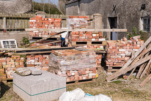 Pallets of reclaimed bricks sit at a building site.