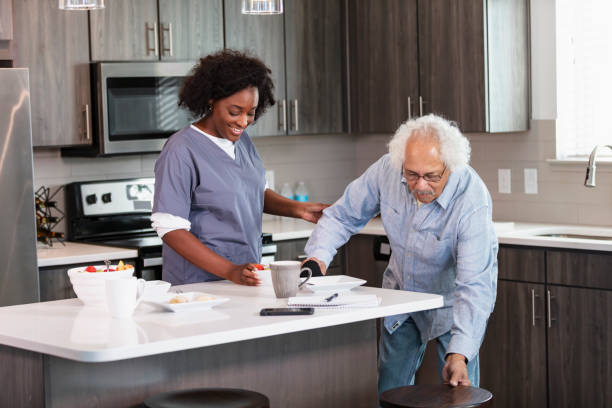 istock Home caregiver helps senior man in kitchen 1397412577