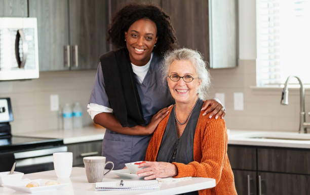 Senior woman in kitchen with home caregiver stock photo