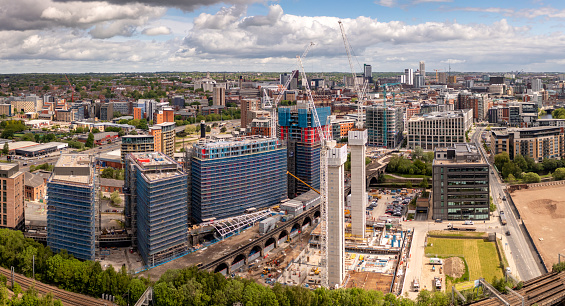 An aerial cityscape view of tall skyscrapers under construction with large cranes lifting equipment in Leeds city centre