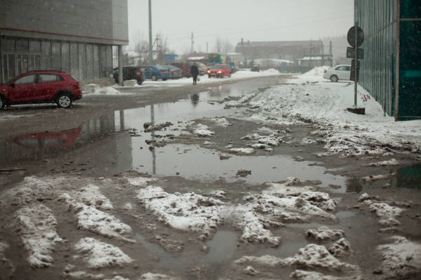 istock Muddy puddle of melted snow on road. Uncleaned parking. 1397413699
