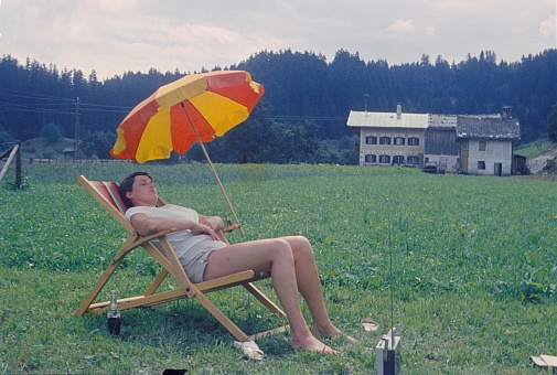 Bavaria, Germany, 1963. Recreation in the countryside. A vacationer (woman) take a nap in a deckchair on a meadow.