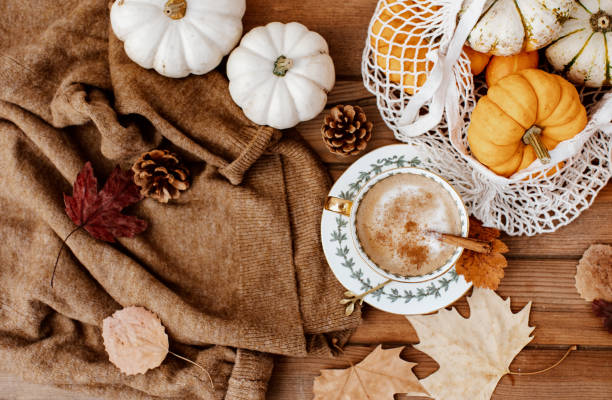 istock Autumn fall composition. Wooden desk table with warm sweater, hot coffee, hat and pumpkin. Flat lay, top view. Nordic, hygge, cozy home concept 1397414762