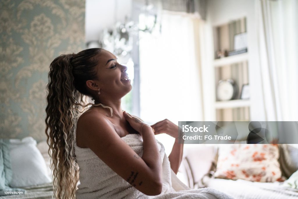 Young woman applying moisturizer on the body at home One Woman Only Stock Photo