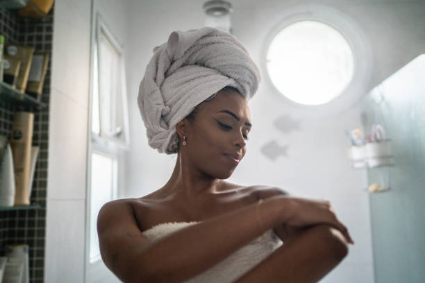 young woman applying moisturizer on the body after shower at home - joint bathroom stok fotoğraflar ve resimler