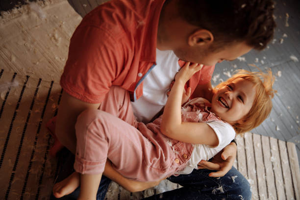 istock Joyful girl in pink and dad playing with feathers 1397414901